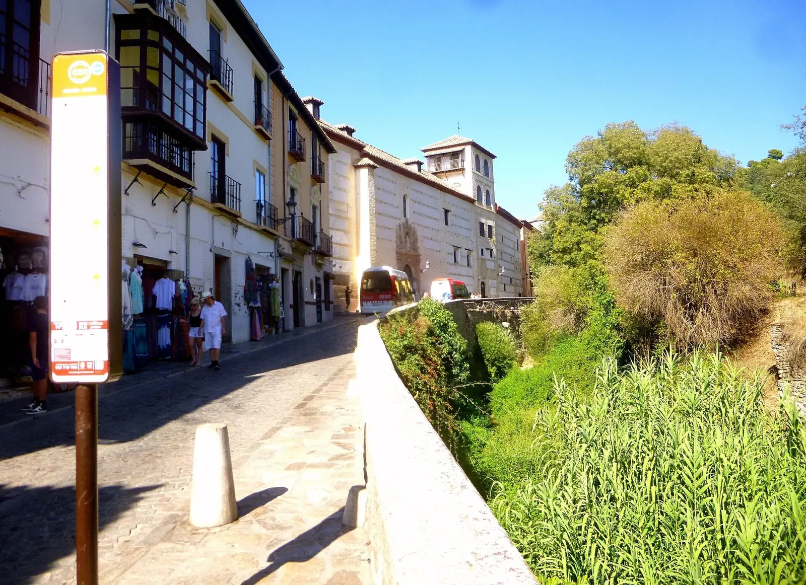 The Carrera del Darro in Granada, a cobbled street beside the river bank with old houses on the left and green reeds on the right
